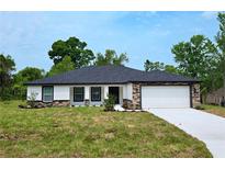Charming single-story home featuring stone accents, a well-manicured lawn, and a two-car garage at 9482 Noddy Tern Rd, Weeki Wachee, FL 34613