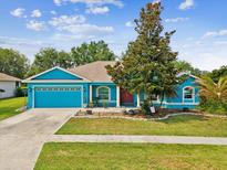 Charming blue single-story home featuring a well-manicured lawn and beautiful mature trees at 2255 Long View Cir, Brooksville, FL 34604