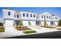 Charming light blue townhomes with well-manicured lawns on a clear, sunny day create an inviting curb appeal at 11410 Spectacled Dr, New Port Richey, FL 34654
