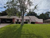 Charming single-story home with a well-manicured lawn and mature tree in a residential neighborhood, garage on the left side at 1221 Etta Ave, Spring Hill, FL 34609