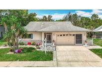 Charming single-story home featuring a well-manicured lawn, lush landscaping, and an attached two-car garage at 13003 Sandburst Ln, Hudson, FL 34667