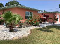 Charming home features a colorful landscaped front yard with vibrant flowers and a small palm tree at 406 Driftwood E Dr, Palm Harbor, FL 34683