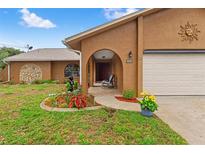 Charming single-story home with beautiful landscaping, an arched entry, and a welcoming front porch at 4190 Lema Dr, Spring Hill, FL 34609
