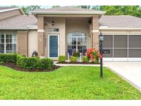 Charming home featuring a blue front door, lovely front yard, and a screened 2 car garage at 7367 Willow Brook Dr, Spring Hill, FL 34606
