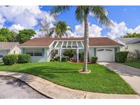 Charming single-story home featuring a well-maintained lawn, blue trim, and a pergola-covered entrance at 8021 Wildflower Row, Hudson, FL 34667