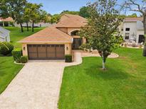 Charming single-story home featuring a tile roof, paver driveway, and mature landscaping at 11350 Copley Ct, Spring Hill, FL 34609