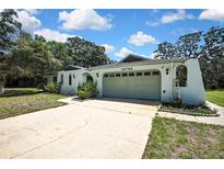 Charming single-story home featuring a two-car garage, well-maintained lawn, and inviting curb appeal on a sunny day at 12722 Oak Tree Dr, Hudson, FL 34667