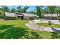 Spacious front yard featuring a circular driveway leading to a home with stone accents and lush landscaping at 21000 Exeter Ct, Brooksville, FL 34601