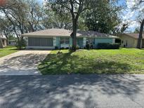 Charming home with a well-maintained lawn, mature trees, and a screened-in garage at 2158 Clayton Ave, Spring Hill, FL 34609