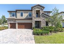 Stunning two-story home boasts a stone facade, three-car garage, and meticulously landscaped front yard at 3767 Dragonfly Trl, Odessa, FL 33556