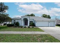 Charming single-story home featuring a well-manicured lawn and a three car garage at 4048 St Ives Blvd, Spring Hill, FL 34609