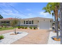 Charming single-story home featuring a brick driveway, stone accents, and well-manicured landscaping at 5045 Pelican Dr, New Port Richey, FL 34652