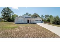 Charming single-story home with well-manicured lawn and a two-car garage on a sunny day at 6309 Covewood Dr, Spring Hill, FL 34609
