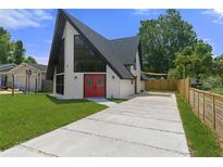 A-frame home showcasing unique architecture, bright red doors, and a well-maintained front yard at 7422 New York Ave, Hudson, FL 34667