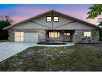 Charming single-story home featuring stone accents, a two-car garage, and a well-maintained front yard at 8568 Heather Blvd, Weeki Wachee, FL 34613