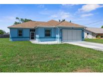 Charming blue single-story home featuring a well-manicured lawn and a two-car garage at 9251 Geneva St, Spring Hill, FL 34608