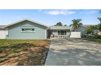 Charming single-story home with a well-maintained lawn, long driveway and decorative landscaping at 1004 Peninsula Ave, Tarpon Springs, FL 34689