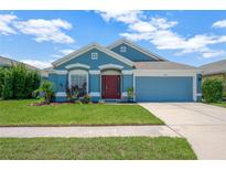 Charming one-story home with blue exterior, well-manicured lawn and landscaping, and a two car garage at 1009 Summer Breeze Dr, Brandon, FL 33511