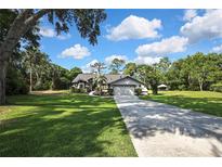 Charming single-story home with mature landscaping and a long driveway, nestled amidst lush greenery and blue skies at 13460 Pia Ct, Spring Hill, FL 34609