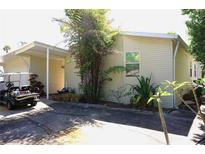 Home exterior featuring vinyl siding, lush foliage, covered parking, and a golf cart for convenient transportation at 20960 Little Magens Loop, Lutz, FL 33558