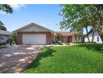 Charming single-story home featuring a brick facade, manicured lawn, and spacious two-car garage at 2866 Thistle N Ct, Palm Harbor, FL 34684