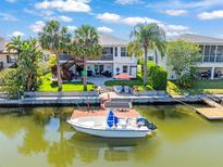 Beautiful waterfront home with boat dock, lush landscaping and outdoor seating under a red umbrella at 4292 Tahiti Dr, Hernando Beach, FL 34607
