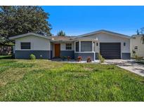 Charming single-story home with a well-maintained lawn, neutral colors, and an attached garage in a sunny setting at 6989 300 Th N Ave, Clearwater, FL 33761