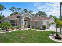 Charming single-story home with lush landscaping, manicured lawn, and an attached two-car garage at 9019 Flagstick Ln, Hudson, FL 34667