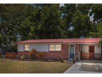 Charming single-story home featuring a red metal roof, brick accents, and a well-maintained front yard at 9306 21St, Tampa, FL 33612