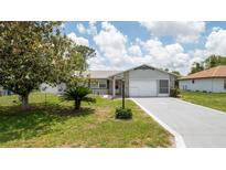 Charming single-story home featuring a well-maintained lawn, mature tree, and a spacious driveway leading to an attached garage at 10386 Myra St, Spring Hill, FL 34608