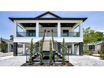 Stunning two-story home featuring a charming front porch, black railings, and well-maintained landscaping at 111 E Cedar St, Tarpon Springs, FL 34689