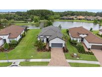 A stunning aerial view of a single-story home with a gray roof, nestled beside a serene lake and lush greenery at 11398 Juglans Dr, Odessa, FL 33556
