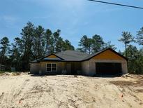 An exterior view of a single-Gathering home, revealing its block construction, dark roof, and garage in a natural setting at 11406 Labrador Duck Rd, Weeki Wachee, FL 34614