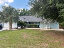 Charming single-story home with mature trees, a statue, and well-maintained lawn at 12090 Stoneville Ct, Spring Hill, FL 34609