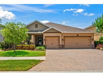 Charming home featuring a well-manicured lawn, brick driveway, and a two-car garage, perfect for suburban living at 1760 Fox Grape Loop, Lutz, FL 33558