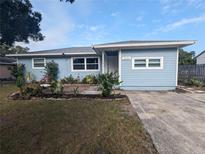 Charming single-story home with light blue siding, manicured front garden, and a cozy brick-paved seating area at 2004 Culberson Ave, Dunedin, FL 34698