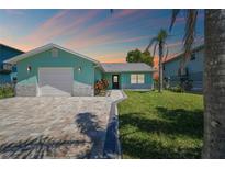 Charming aqua home with a paver driveway, complemented by lush green lawn and landscaping at 4482 Kingston Dr, Hernando Beach, FL 34607