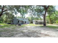 Spacious backyard featuring the main house, a detached guest house, a fire pit, and mature trees at 6234 Cyril Dr, Dade City, FL 33523