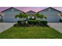 Charming single-story home featuring a well-manicured lawn, lush landscaping, and a symmetrical facade with a two-car garage at 8431 Ocean Tides Cv, Parrish, FL 34219