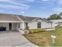 Charming single-story home with a well-manicured lawn, bright exterior paint and a two-car carport at 9212 Estrada Pl, New Port Richey, FL 34655