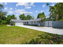 Charming single-story home featuring a large front yard, long driveway, and decorative privacy gate at 10301 Nina Ct, New Port Richey, FL 34654