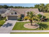 Charming one-story home featuring a well-manicured lawn with a palm tree and a classic two-car garage at 1049 Larkin Rd, Spring Hill, FL 34608