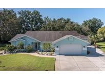 Charming single-story home with a well-manicured lawn and a two-car garage and light blue exterior at 3609 Montclair Dr, New Port Richey, FL 34655