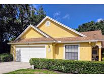 Charming yellow home featuring a two-car garage, and well-maintained front yard, creating a welcoming curb appeal at 3627 Muirfield Ct # 3627, New Port Richey, FL 34655