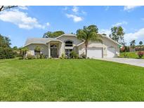 Charming single-story home featuring a well-manicured lawn, two-car garage, and elegant front entrance at 487 Waterloo Ct, Spring Hill, FL 34609