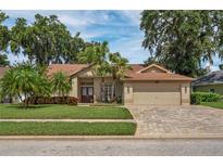 Beautifully landscaped single Gathering home featuring a manicured lawn, a brick paved driveway and mature trees at 4923 Fort Peck Rd, New Port Richey, FL 34655