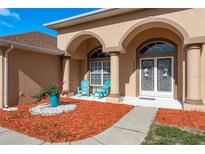 Inviting front porch with stylish columns, tiled floor, seating, and beautiful landscaping at 5423 Abagail Dr, Spring Hill, FL 34608