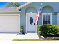 Inviting front entrance with an oval-window door, attached garage, and neatly manicured landscaping at 6172 Raleigh St, Spring Hill, FL 34606