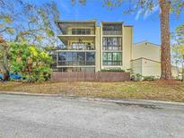 Beige condo building with screened patios surrounded by lush landscaping and trees against a blue sky at 700 Starkey Rd # 622, Largo, FL 33771