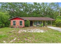 Charming single-story home with brick accents, a cozy carport, and lush greenery in a serene setting at 8102 Fort Dade Ave, Brooksville, FL 34601